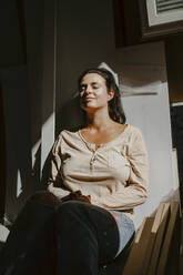 Smiling woman enjoying sunlight during home renovation - MASF43551