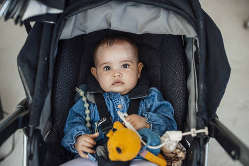 Baby girl with stuffed toy sitting in baby carriage - JOSEF23833