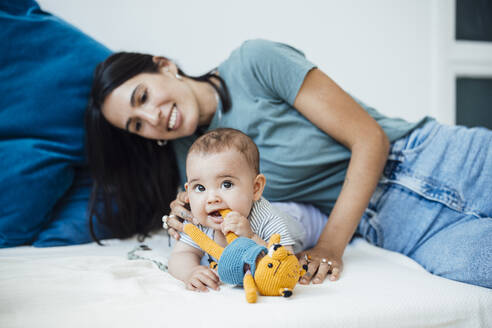 Baby-Mädchen spielt mit Plüschtier von Mutter auf dem Bett zu Hause - JOSEF23861