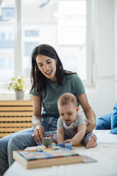 Mutter von Baby Mädchen spielen mit Spielzeug auf dem Bett zu Hause - JOSEF23862