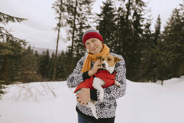 Smiling man with pet dog in winter forest - MCHF00017