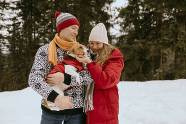 Happy couple with pet dog in winter forest - MCHF00019