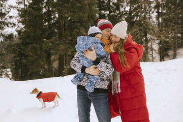 Vater und Mutter mit Sohn im Schnee stehend im Winter - MCHF00021