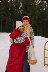 Glückliches Paar umarmt sich im Winterwald - MCHF00025