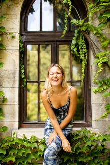 Pretty young woman by old house with ivy - INGF13115