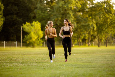 Two pretty young women running in the park - INGF13121