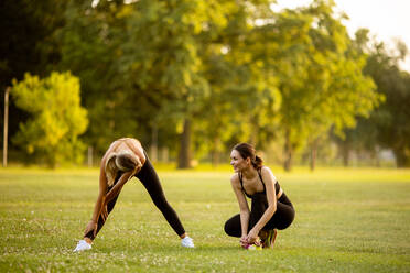 Two pretty retty young woman doing stretching in the park - INGF13123