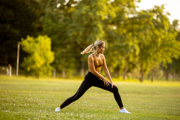 Pretty young woman doing stretching in the park - INGF13124