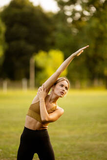 Pretty young woman doing stretching in the park - INGF13125