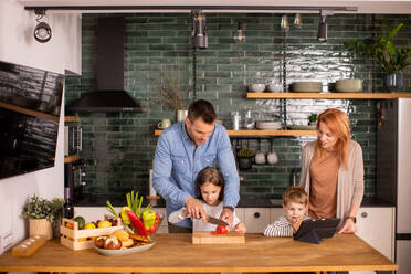 Happy young family preparing vegetables in the kitchen - INGF13140