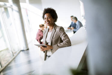 Young African American businesswoman standing and using digital tablet in the modern office - INGF13170