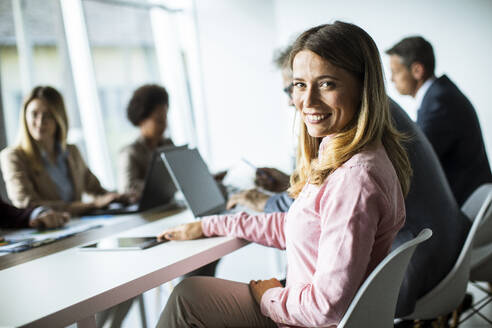 Pretty young woman smiling during successful business meeting in the modern office - INGF13172