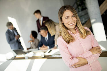 Business woman standing with her staff have a meeting in the background - INGF13174