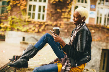 Pretty young black woman with mobile phone and coffee cup - INGF13186