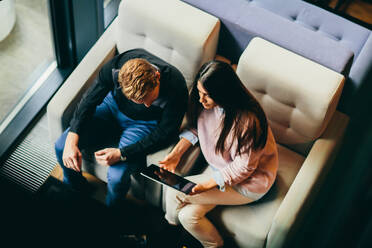 Young modern couple sitting together and using a tablet, View from above - INGF13200