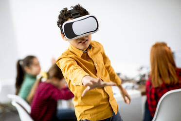 Cute little boy wearing VR virtual reality glasses in a robotics classroom - INGF13213