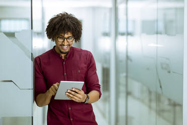 Portrait of african-american young businessman with tablet standing in the office - INGF13227