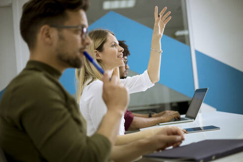 Pretty young woman raised her hand up for question in conference meeting - INGF13247