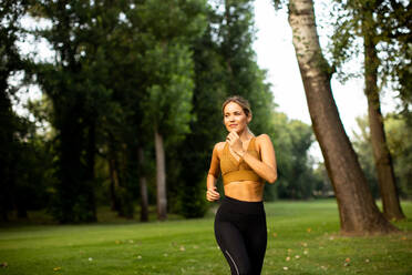 Pretty young woman running in park - INGF13280