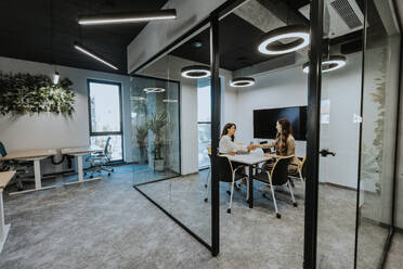 Young business women discussing in cubicle at the modern office - INGF13284