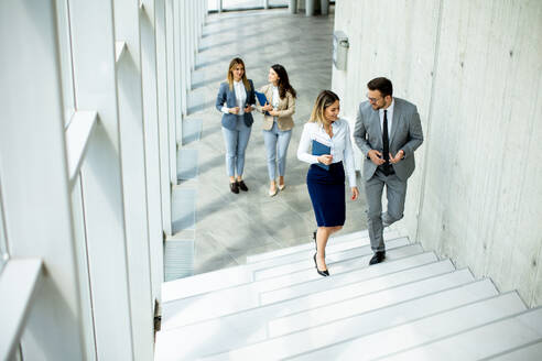 Young startup team have a discussion while climbing on the stairs in the office corridor - INGF13300