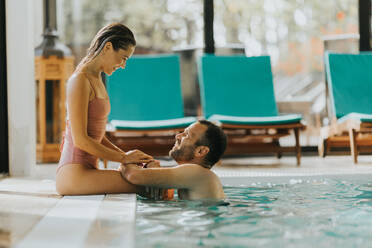 Handsome young couple relaxing in the indoor swimming pool - INGF13305