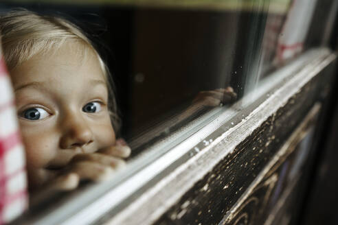 Mädchen schaut durch ein Fenster hinaus - NSTF00023