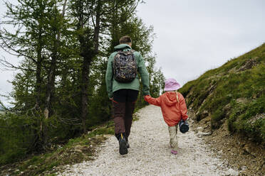 Vater und Tochter halten sich beim Wandern in den Bergen an den Händen - NSTF00029