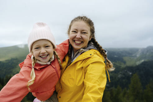 Cheerful mother carrying daughter on mountain - NSTF00032