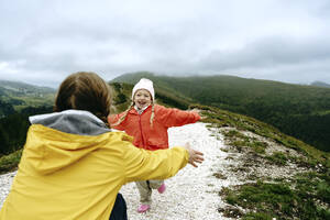 Glückliches Mädchen läuft auf die auf einem Berg hockende Mutter zu - NSTF00033