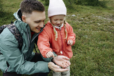 Smiling father showing bug and flower to daughter - NSTF00037