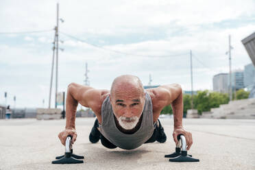 Active senior man doing push-ups on handles - OIPF04056