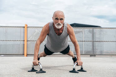 Active senior man doing plank exercise on handles - OIPF04058