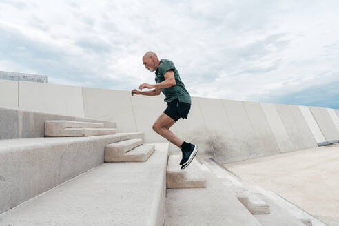 Retired active senior man jumping on steps - OIPF04066