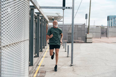 Älterer Mann joggt am Zaun - OIPF04070