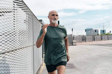 Active senior man jogging by fence - OIPF04071