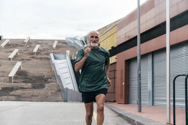 Entschlossener älterer Mann joggt auf dem Fußweg - OIPF04097