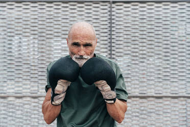 Confident senior man practicing with boxing gloves - OIPF04106