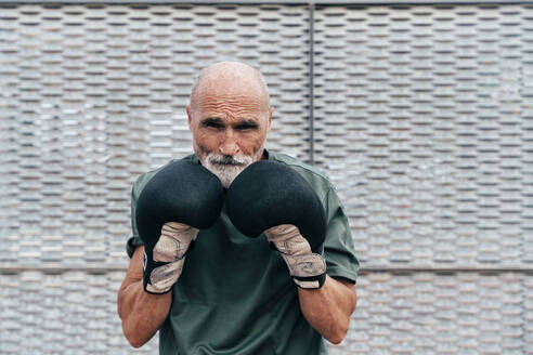 Selbstbewusster älterer Mann beim Üben mit Boxhandschuhen - OIPF04106