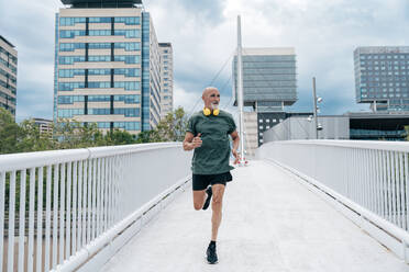 Determined senior man running on footbridge - OIPF04122
