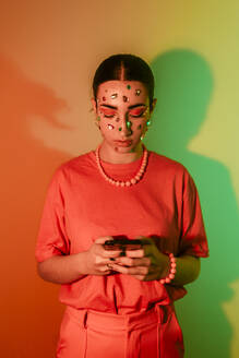 Young woman using smart phone against neon background - EGHF00860