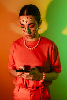 Woman using smart phone against colorful background - EGHF00861