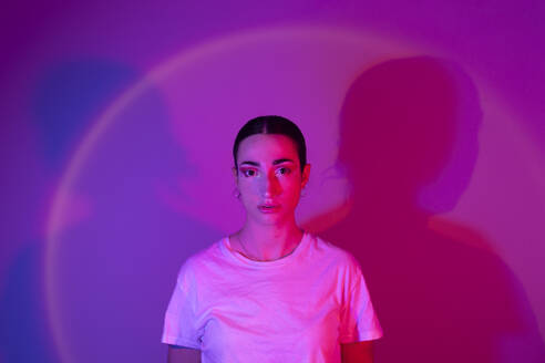 Junge Frau in Neonbeleuchtung vor einem Hintergrund mit Farbverlauf - EGHF00869