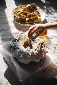 Hand eines Mädchens beim Verzieren von Kuchen auf einem Tisch zu Hause - ASHF00082