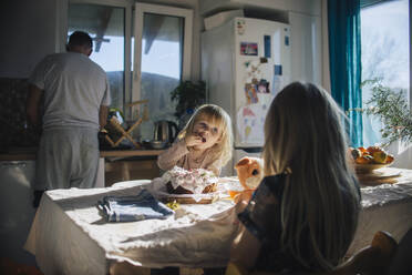 Girl eating cake in kitchen near family at home - ASHF00085