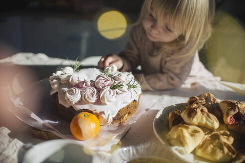 Mädchen dekoriert Kuchen auf dem Esstisch zu Hause - ASHF00092