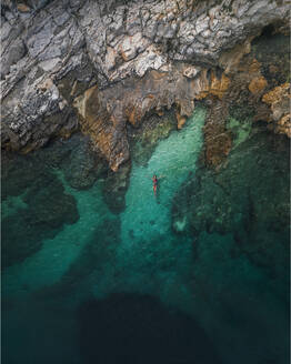 Aerial view of a solitary woman snorkeling in the crystal blue waters of the Adriatic Sea, Primorje-Gorski Kotar, Croatia. - AAEF26250