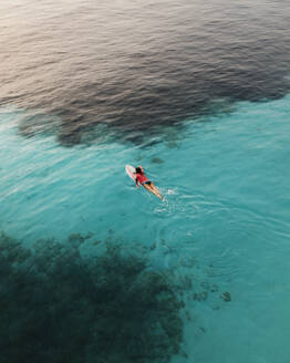 Aerial view of transparent blue water and coastline with active female surfer, Primorje-Gorski Kotar, Croatia. - AAEF26251