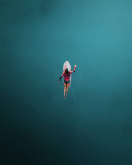 Aerial view of woman surfing with red surfboard in blue ocean, Primorje-Gorski Kotar, Croatia. - AAEF26252