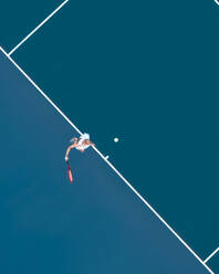 Aerial drone view of a female tennis player laying on a blue tennis court in Melbourne, Victoria, Australia. - AAEF26263